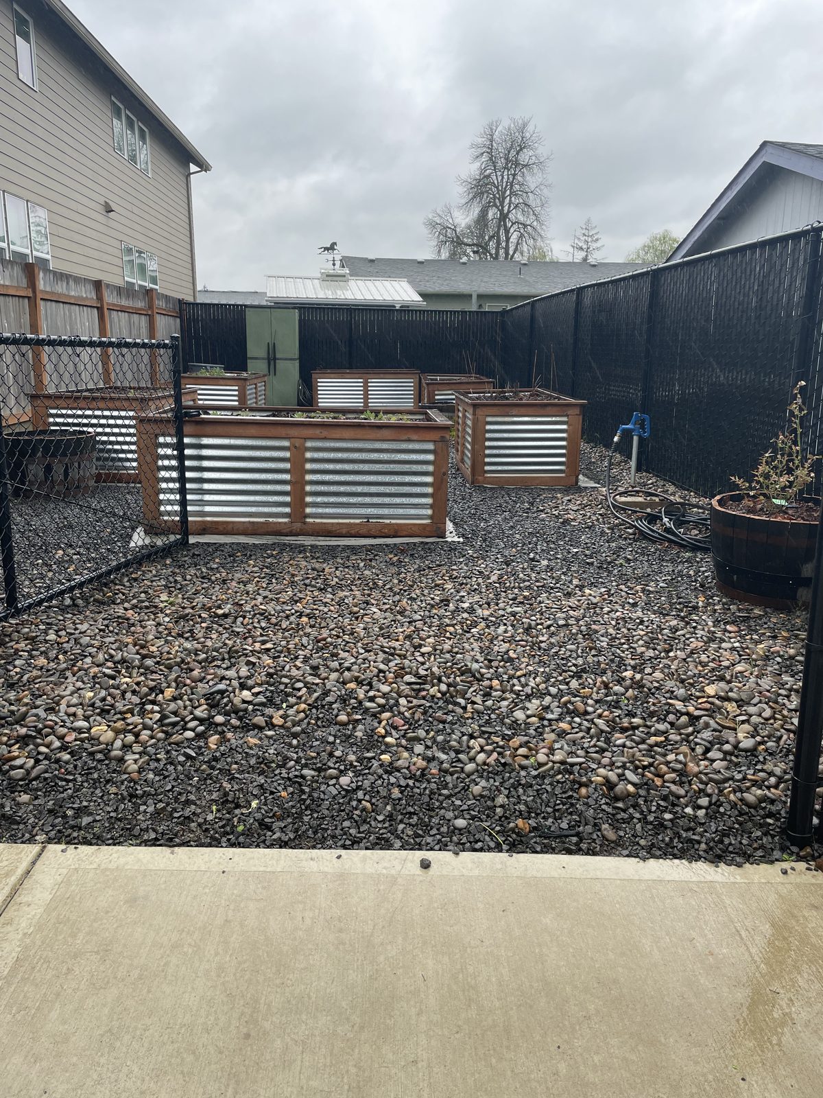 Empty raised beds on bare gravel under a grey sky before planting