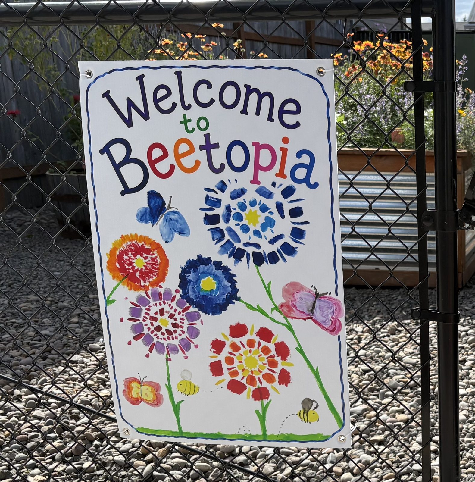 A hand-painted Welcome to Beetopia sign hung on the garden fence