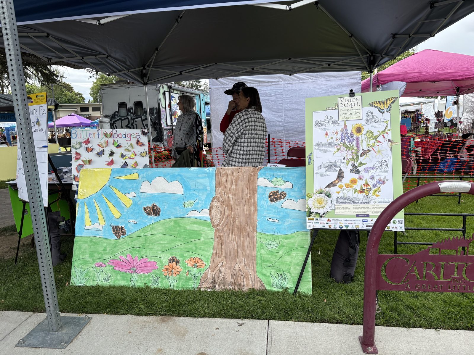 The Carlton Pollinator Project booth at Fun Days with posters, a painted mural, and visitors