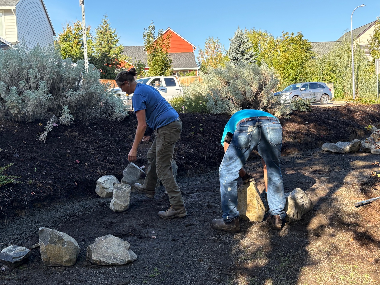 Two volunteers setting edging rocks along a freshly mulched slope at Hawn Creek Pocket Park